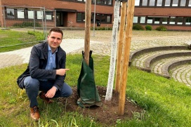 Stadtsprecher Helge Tiemann neben einem von 200 Bewässerungsbeuteln für junge Stadtbäume