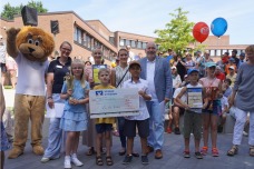 Lions-Maskottchen Leo, Lions-Präsidentin Dr. Lisa Huemke und Bürgermeister Thomas Beckmann überreichen den Gewinnerinnen und Gewinnern des Bü-cherlöwen Cups im Beisein ihrer Lehrerinnen Urkunde, Pokal und einen Scheck über 750 Euro der VR Bank in Holstein für die nächste Klassenfahrt
