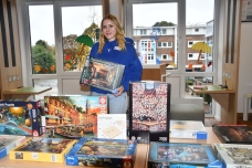 Mitarbeiterin Noelle Griesbach präsentiert eine Auswahl der rund 20 Puzzles, die beim Familiensamstag ihre Besitzer wechseln konnten (Quelle: Stadt Quickborn) PM 363_2 Familiensamstag bringt Leben in die Stadtbücherei